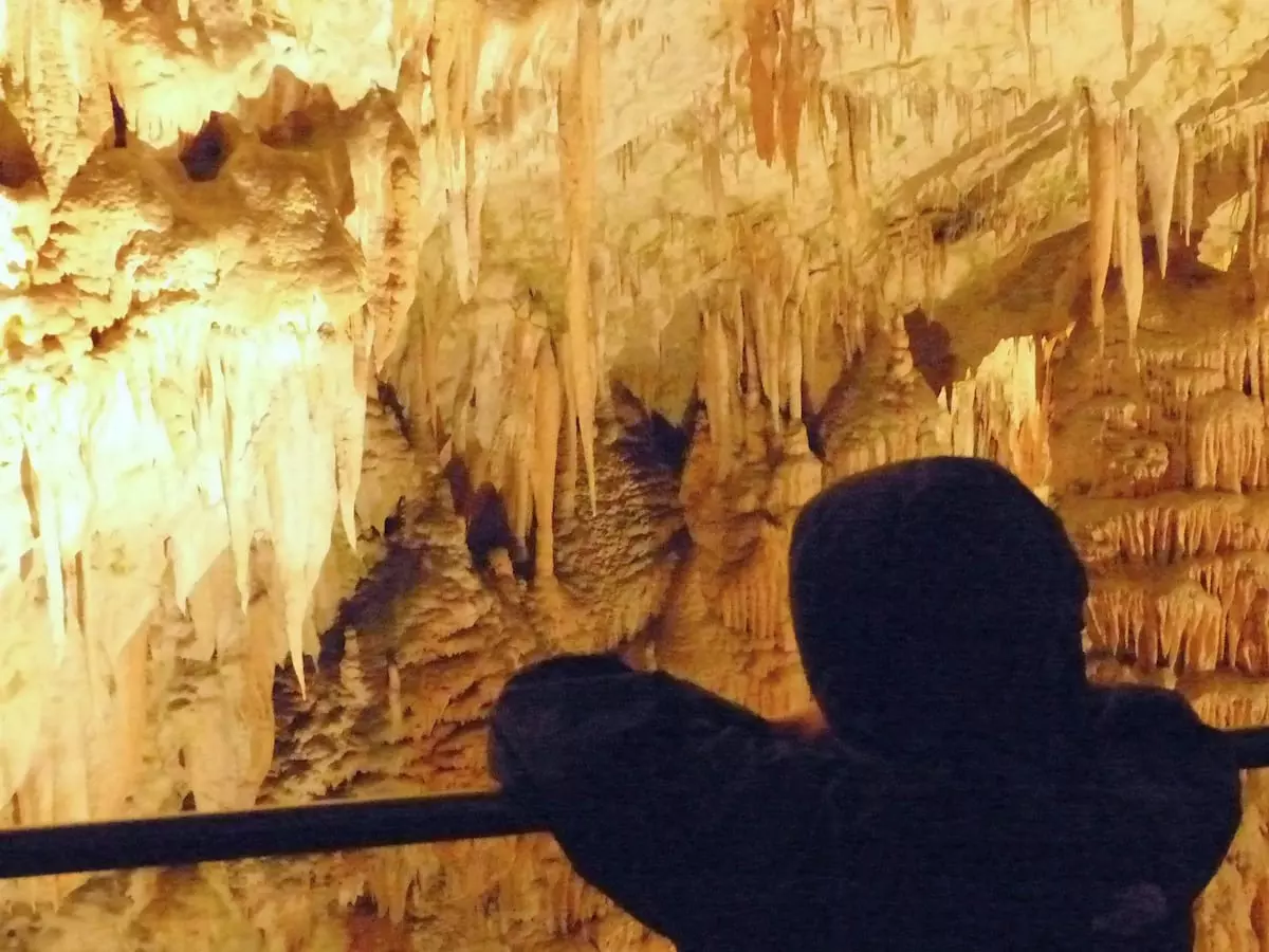 Slowenien Urlaub mit Kind Im Slowenien Urlaub ist ein Kind in einer Kapuzenjacke vertieft in den Anblick der vielen Tropfsteine in den Postoinahöhlen