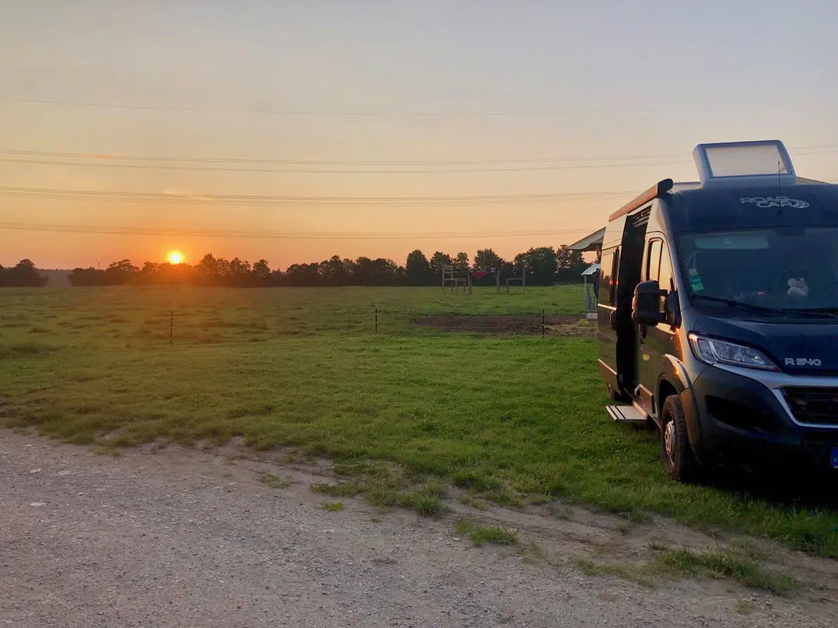 Wohnmobil auf einem Bauernhof-Stellpatz im Sonnenuntergang auf einer Wiese mitten in der Natur
