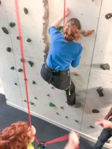 Mutter beim Klettern an der Kletterwand in der Jugendherberge Oberammergau
