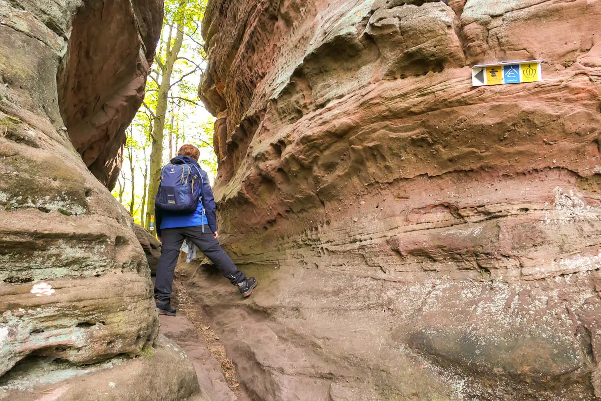 Wanderer an einem Feslendurchbruch im Dahner Felsenland im Pfälzerwald