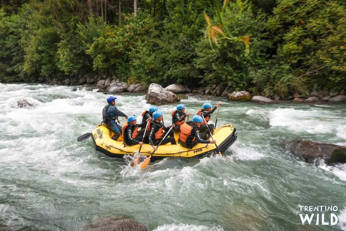 Gelbes Schlauchboot mit 6 Leuten und 1 Guide bei einer Rafting Tour auf dem Wildwasser Fluss Noce im Trentino vor einer Stromschnelle