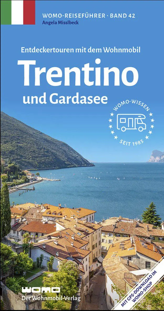 womo-reisefuehrer-trentino Titelbild eines Reiseführers mit dem Titel „Trentino und Gardasee“, das einen malerischen Blick auf den Gardasee zeigt, mit Bergen, blauem Wasser, Booten und Gebäuden im mediterranen Stil im Vordergrund.