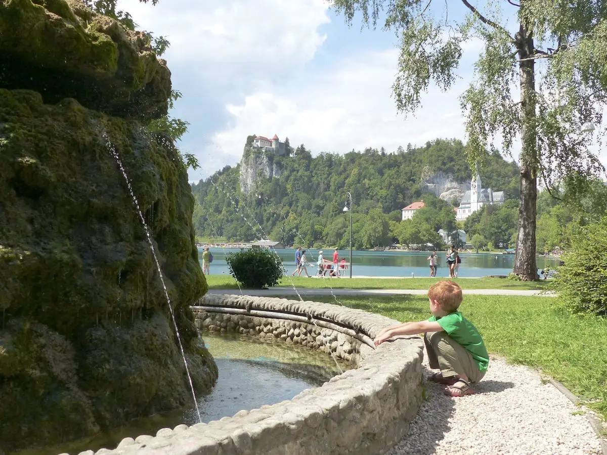 Slowenien Urlaub mit Kindern - Brunnen in Bled mit Burg, See und Kirche
