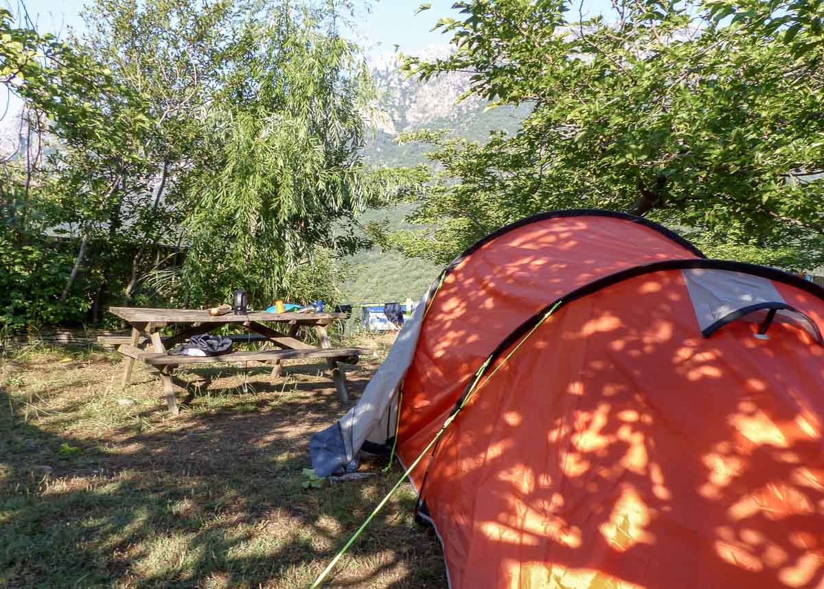 Zelten mit Picknickbank zwischen Büschen in den Bergen