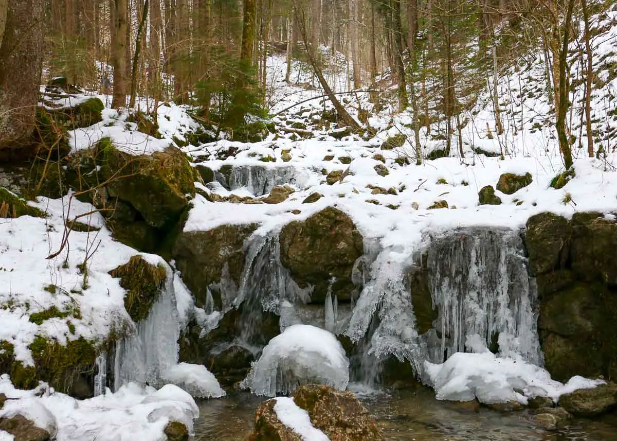 Wasser fall mit Eiszapfen auf dem Wanderweg zur Kolbenalm bei Oberammergau