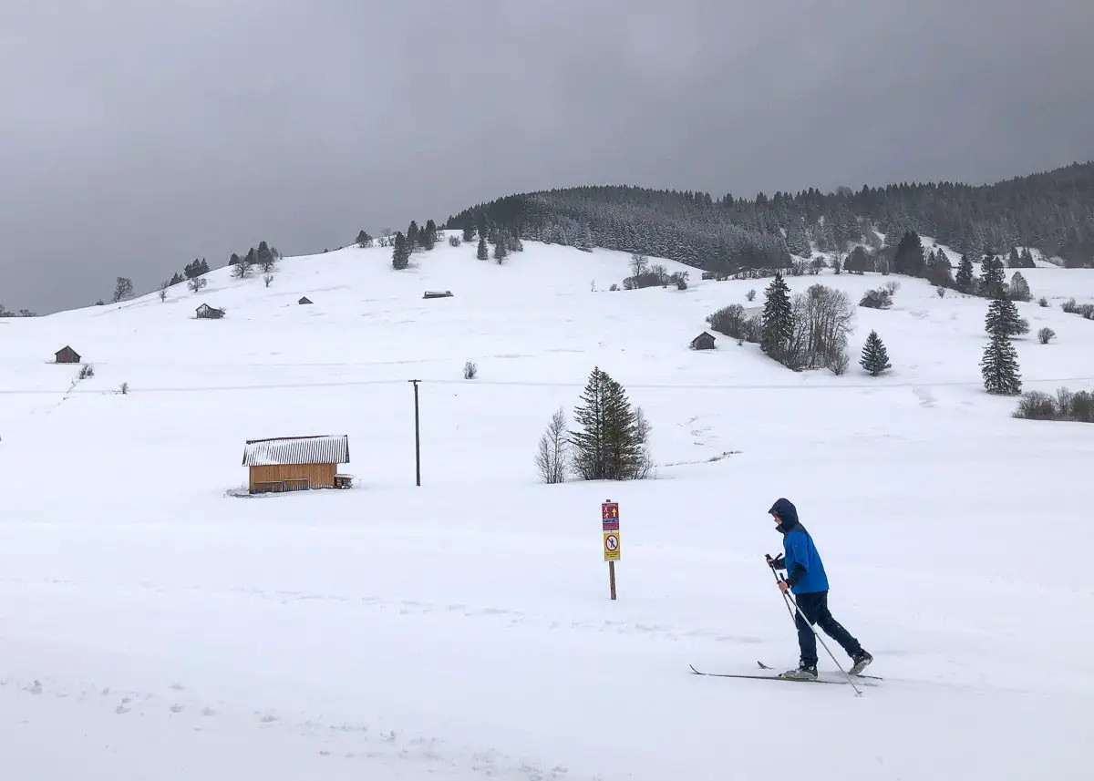 Verschneite Almwiesen bei Oberammergau mit Kindern beim Langlaufen