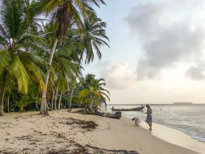 Touristin mit Kindern geht am Palmenstrand auf San Blas Inseln spazieren