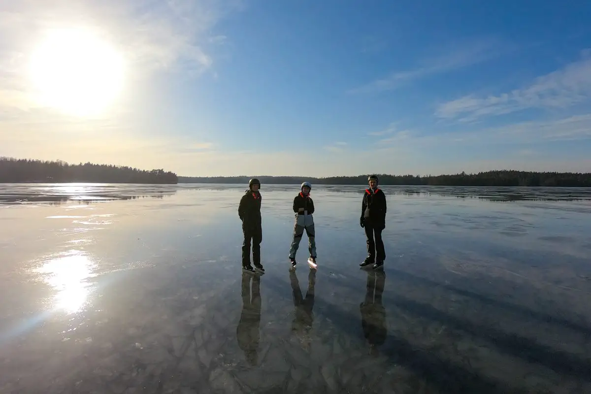 Familie wandert mit Schlittschuhen über einen zugefrorenen See in Schweden (Tiveden)
