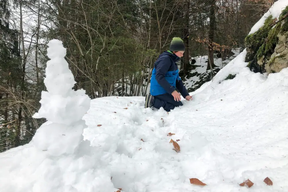 Kind im Schnee beim Schneemann bauen
