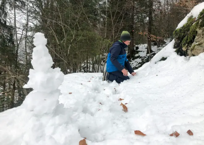 Kind im Schnee beim Schneemann bauen