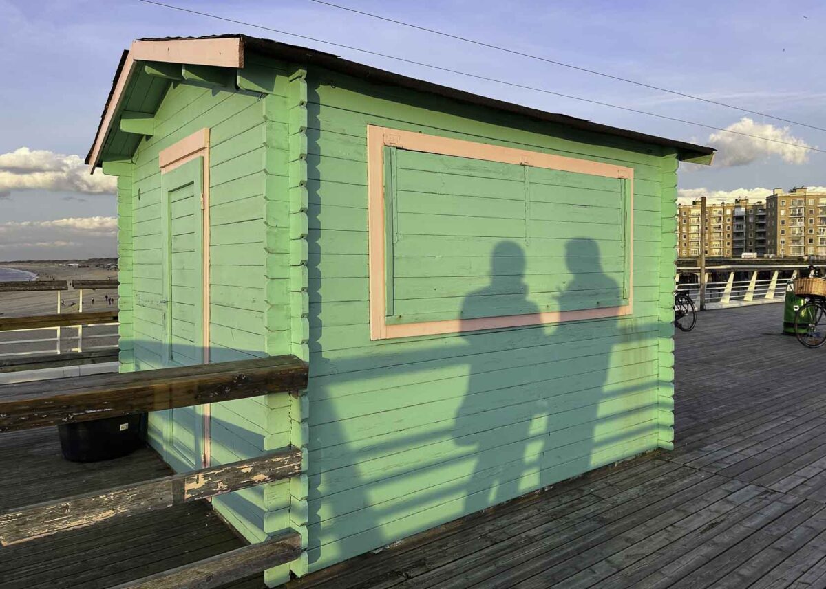 Buntes Kioskhäuschen mit Schatten von Mutter und Kind auf der Seebrücke von Scheveningen
