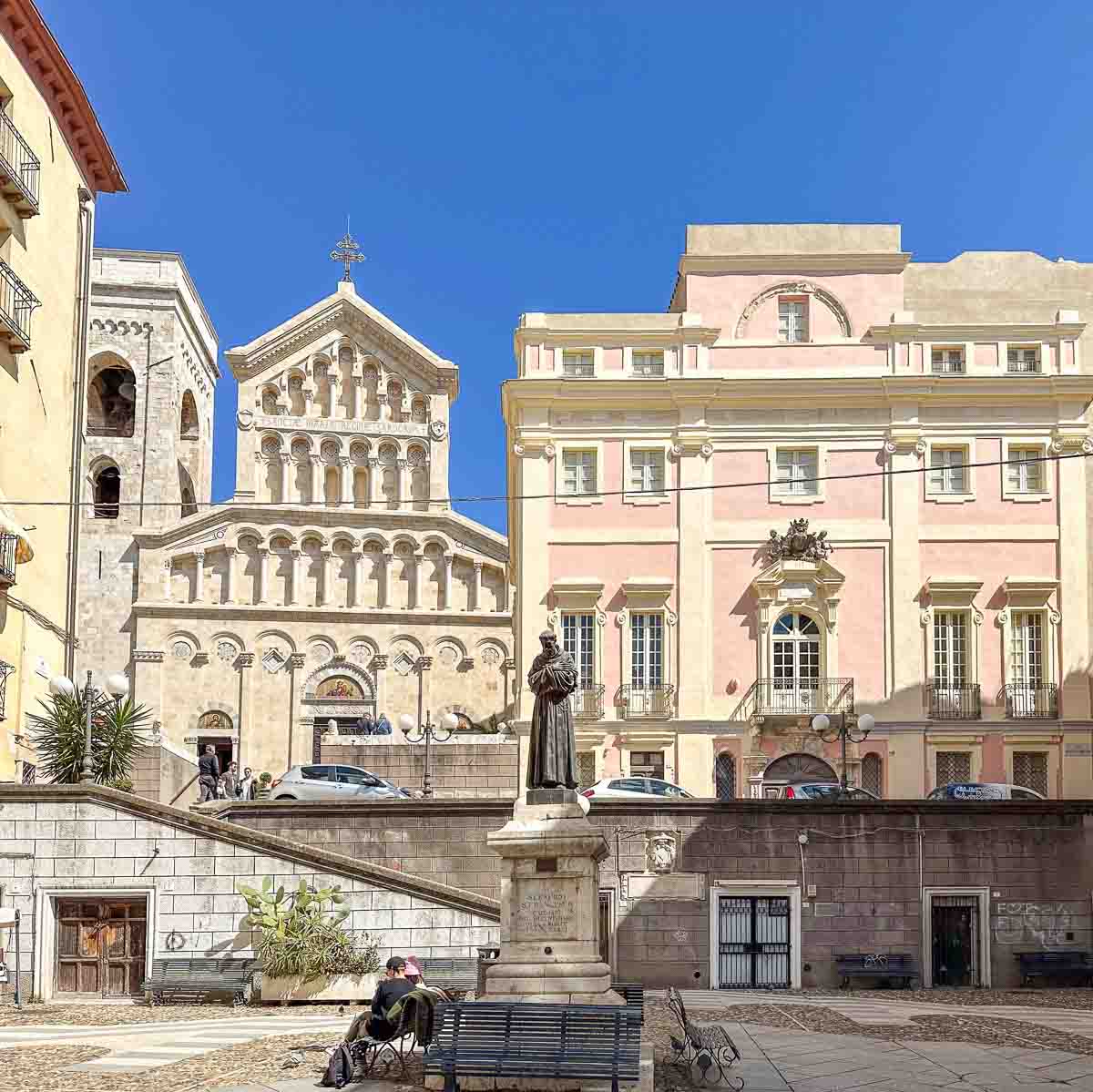 Piazza mit einer Franziskus-Statue und Blick auf eine Kathedrale und ein prachtvolles Stadtpalais in Cagliari Altstadt