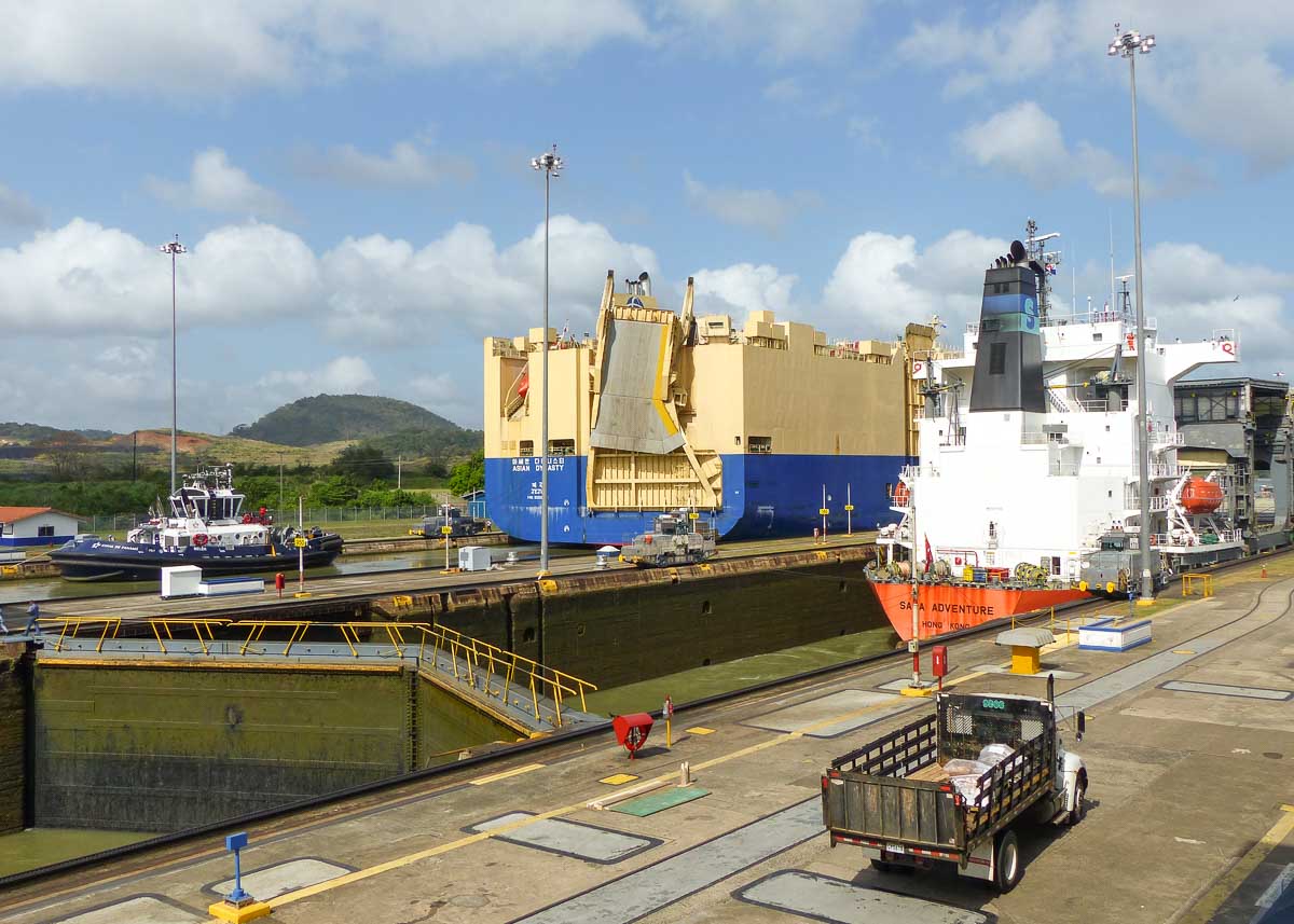 Zwei riesige Frachtschiffe fahren aus der Miraflores Schleuse in den Panamakanal. Die Schleusentore sind halb geöffnet.