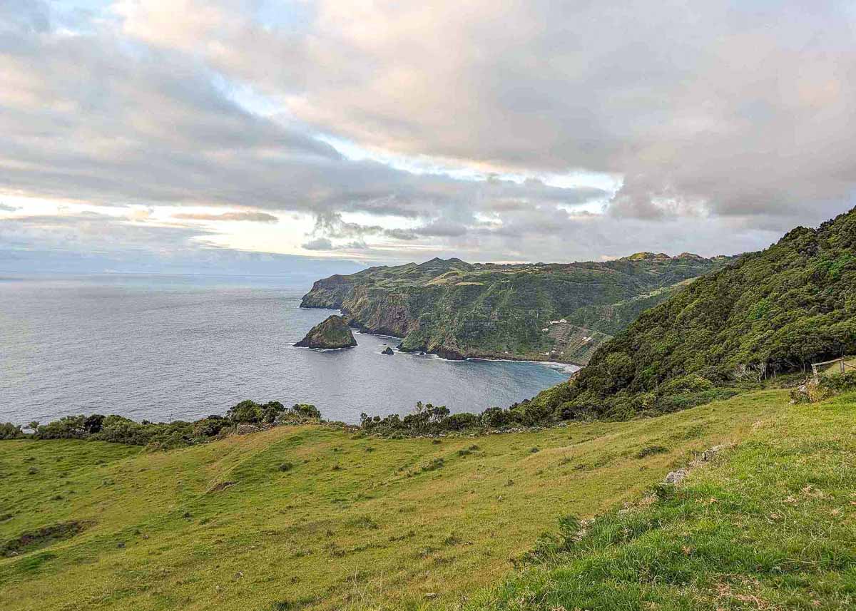Panorama einer grünen Naturlandschaft auf der Azoren-Insel Santa Maria mit Steilküste, Wald und Wiesenhängen.